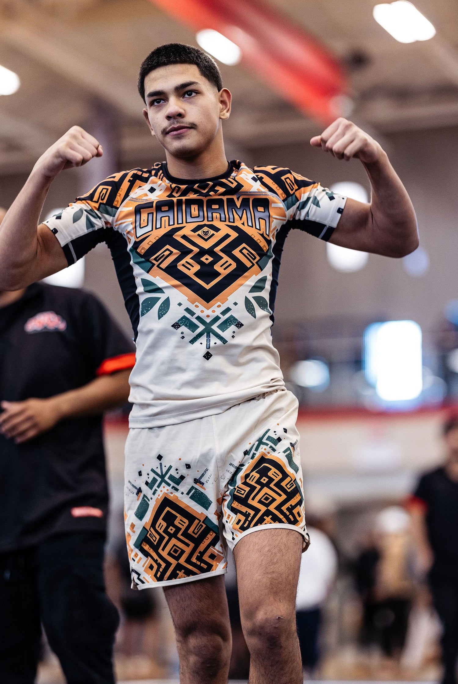 Young man nogi BJJ champion of the ADCC Chicago Open tournament flexing his muscles for the camera wearing the men's Desert Relic board shorts and Jiu Jitsu rashguard by Gaidama.