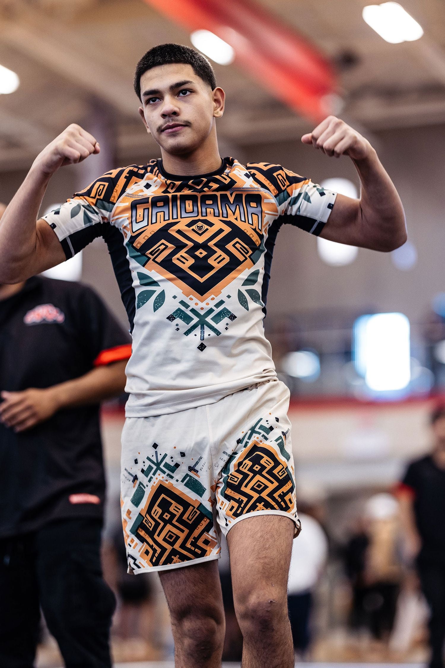 Young man nogi BJJ champion of the ADCC Chicago Open tournament flexing his muscles for the camera wearing the men's Desert Relic board shorts and Jiu Jitsu rashguard by Gaidama.