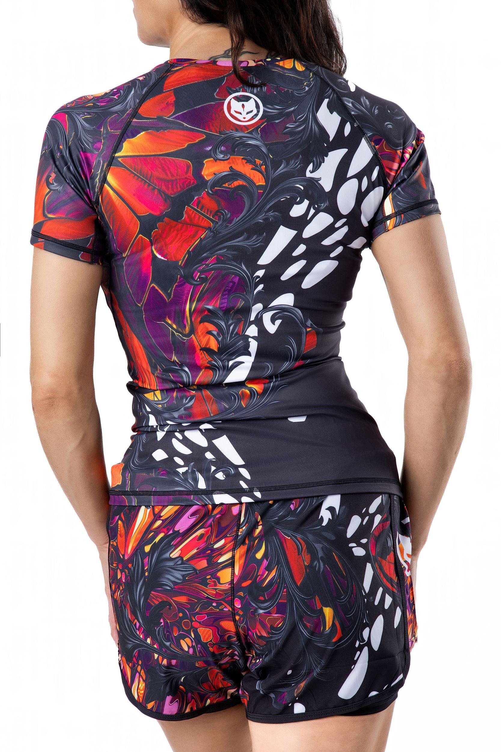 Women's beautiful Monarch butterfly-inspired pink, black, purple, and orange Jiu Jitsu rashguard and board shorts for BJJ, back view.