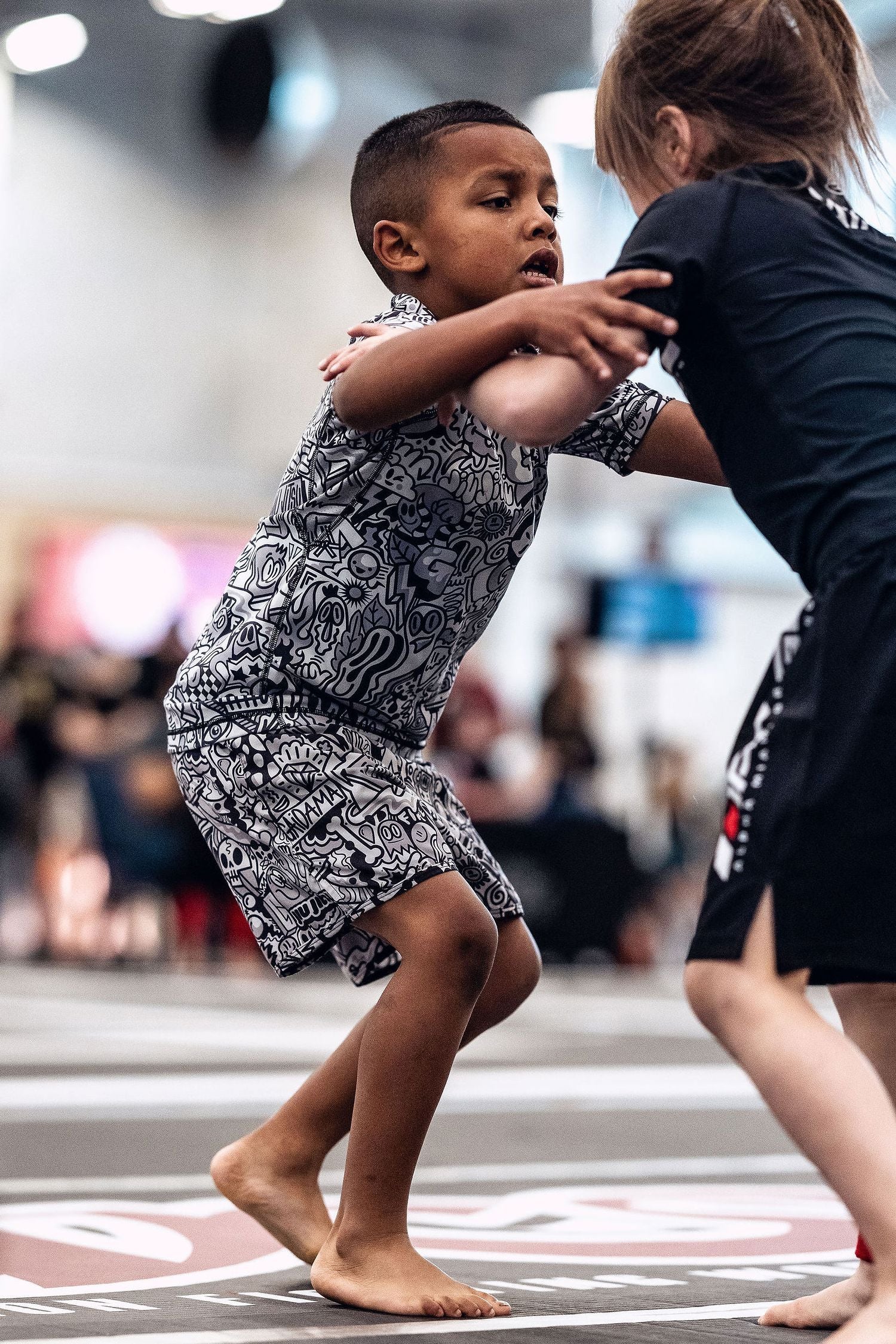 Young boy wearing Gaidama's Wotto Doodle kids rashguard and children's BJJ shorts competing at an ADCC Open nogi Jiu Jitsu tournament.